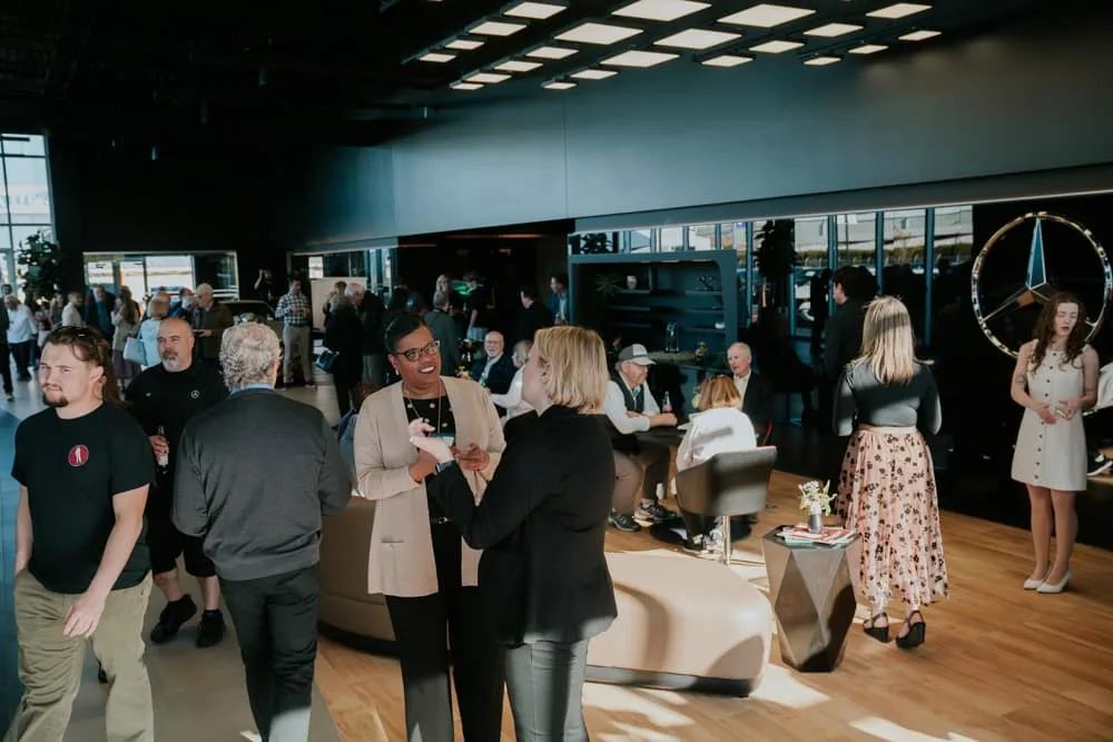 Corporate grand opening event guests inside a luxury dealership showroom
