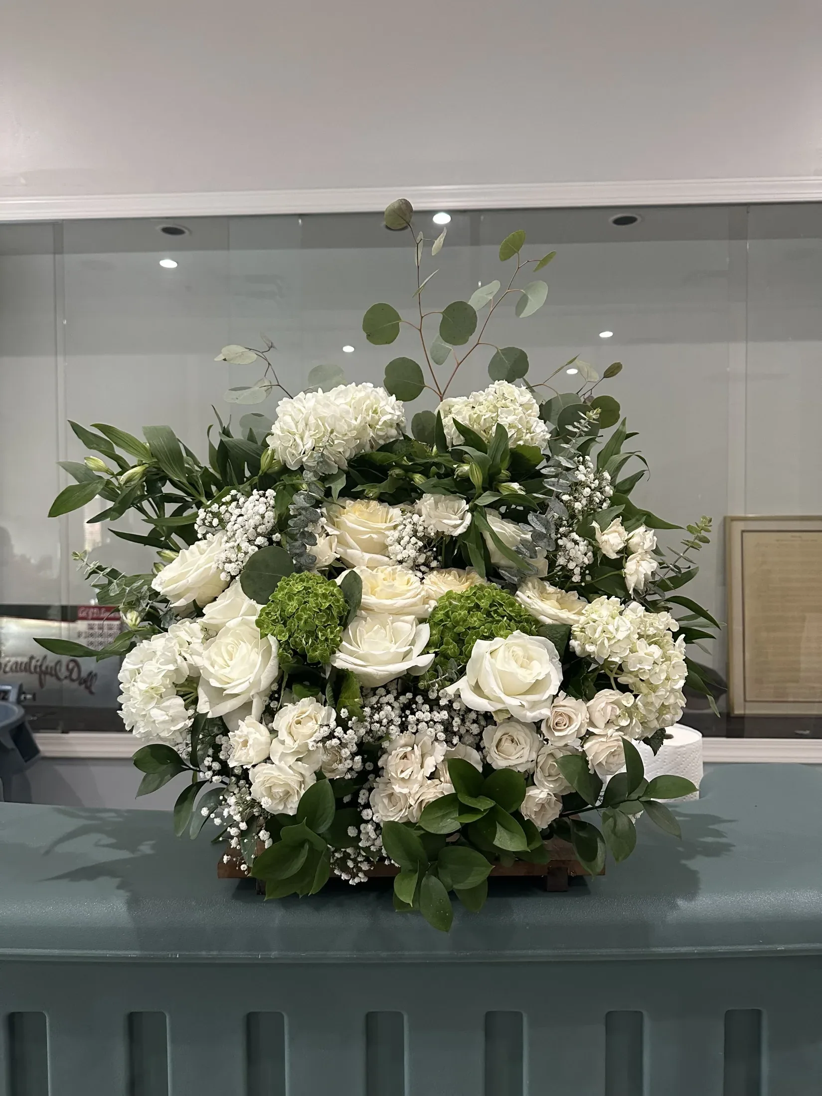 Lush floral arrangement with white roses, hydrangeas, greenery, and baby\'s breath