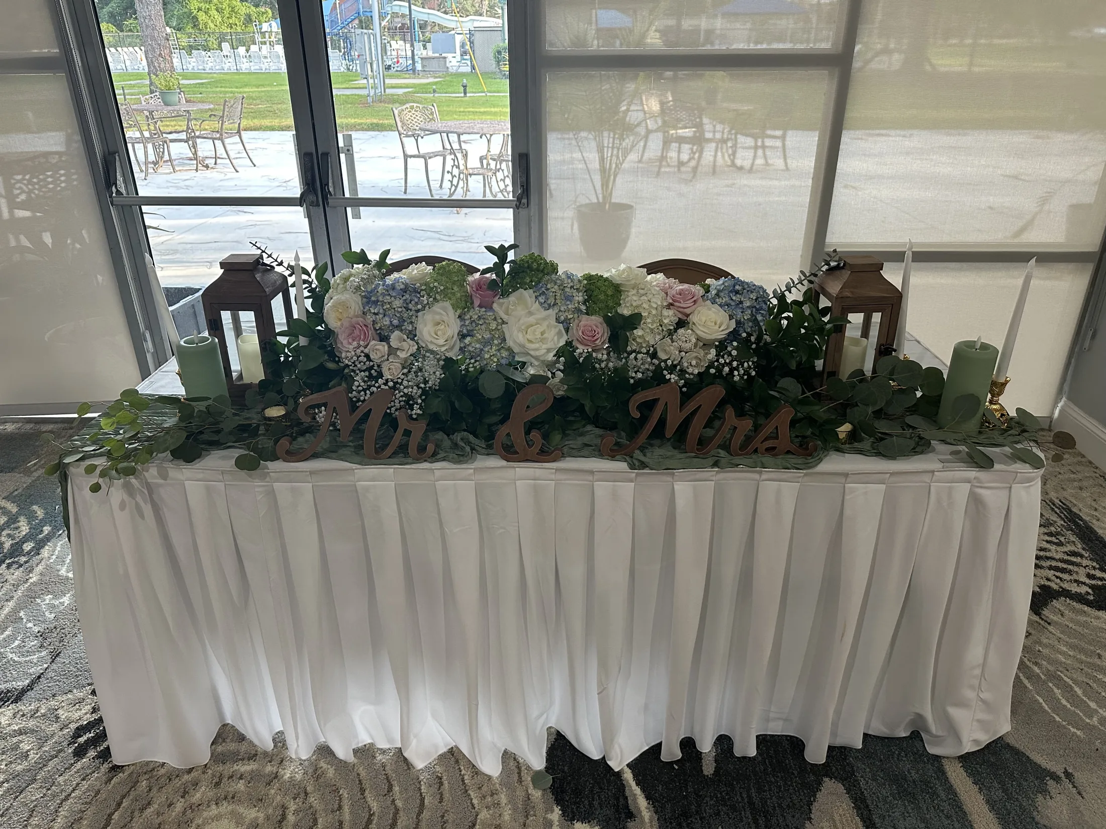 Sweetheart table floral design with hydrangeas, roses, candles, and Mr and Mrs sign